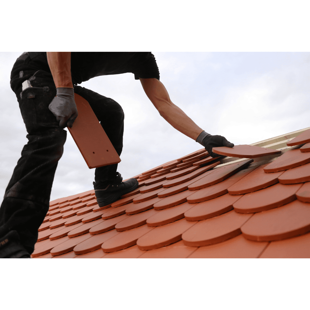Roofer installing terracotta tiles on a roof with precision and expertise.