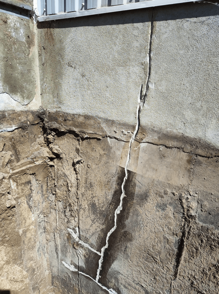 Major vertical crack on an excavated concrete foundation, showing signs of structural deterioration