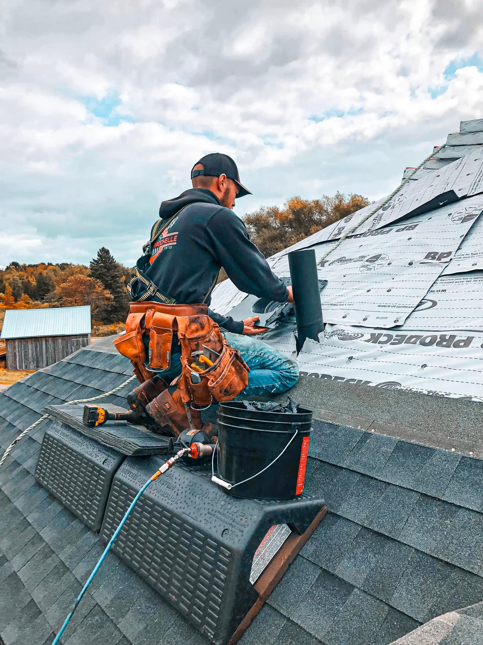 Professional roofer repairing a roof and installing shingles using specialized equipment for a safe roofing project.