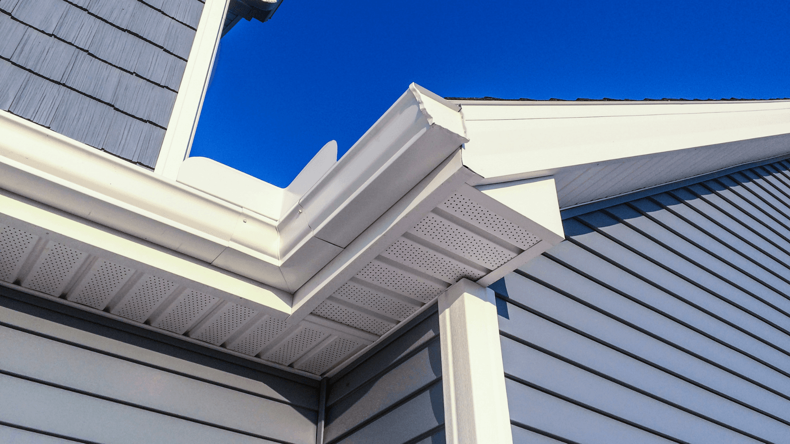 A detailed view of a house's exterior, highlighting the decorative cornice, gutter, and siding.