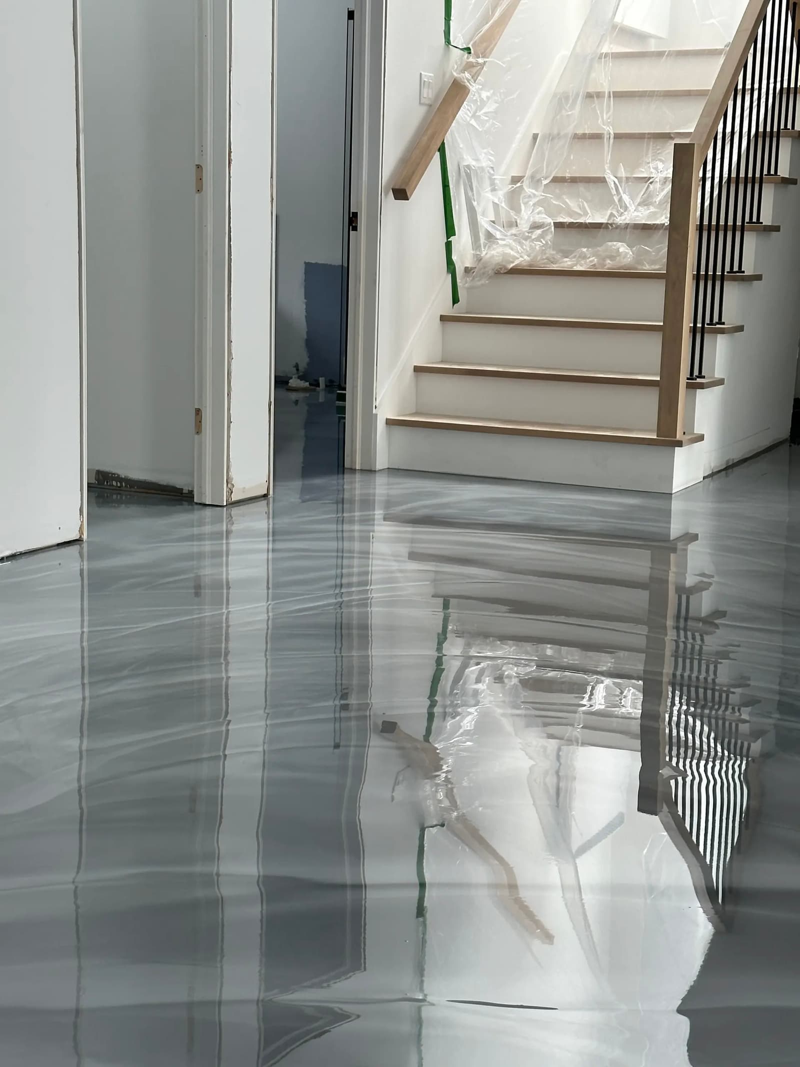 Freshly poured epoxy resin floor with a gray marble effect and ultra-glossy finish in a house under renovation.