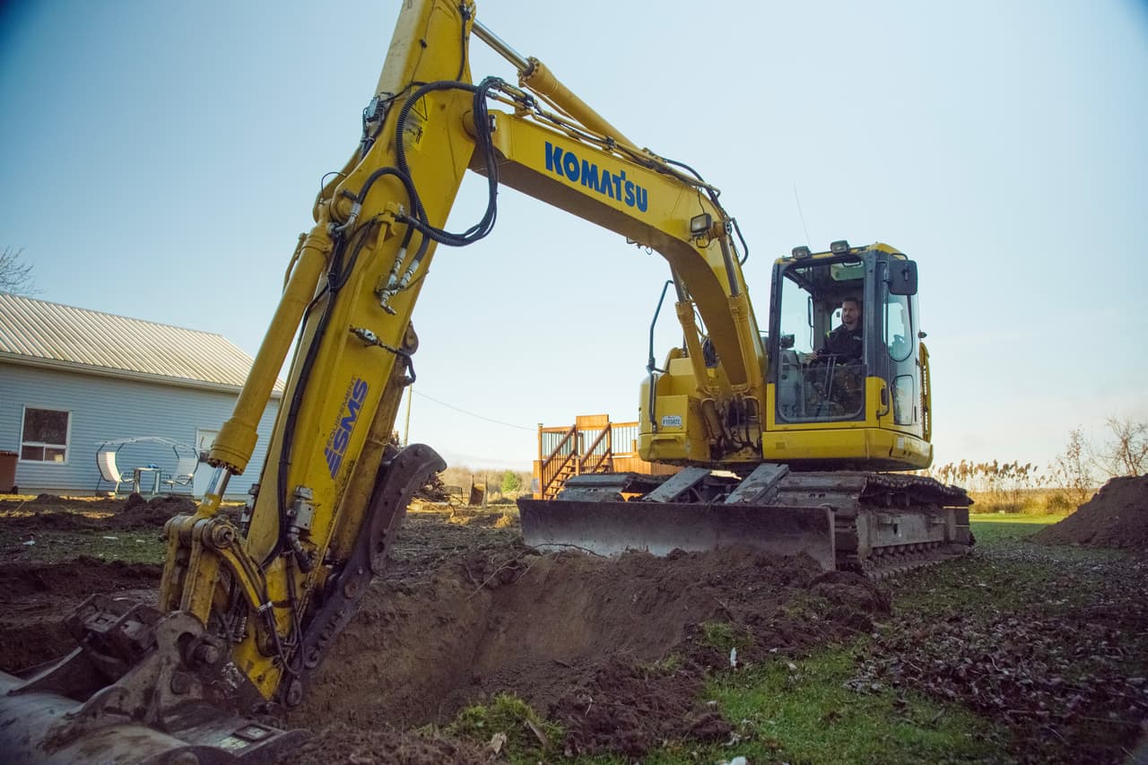 Komatsu excavator digging a trench on a residential lot in preparation for excavation work
