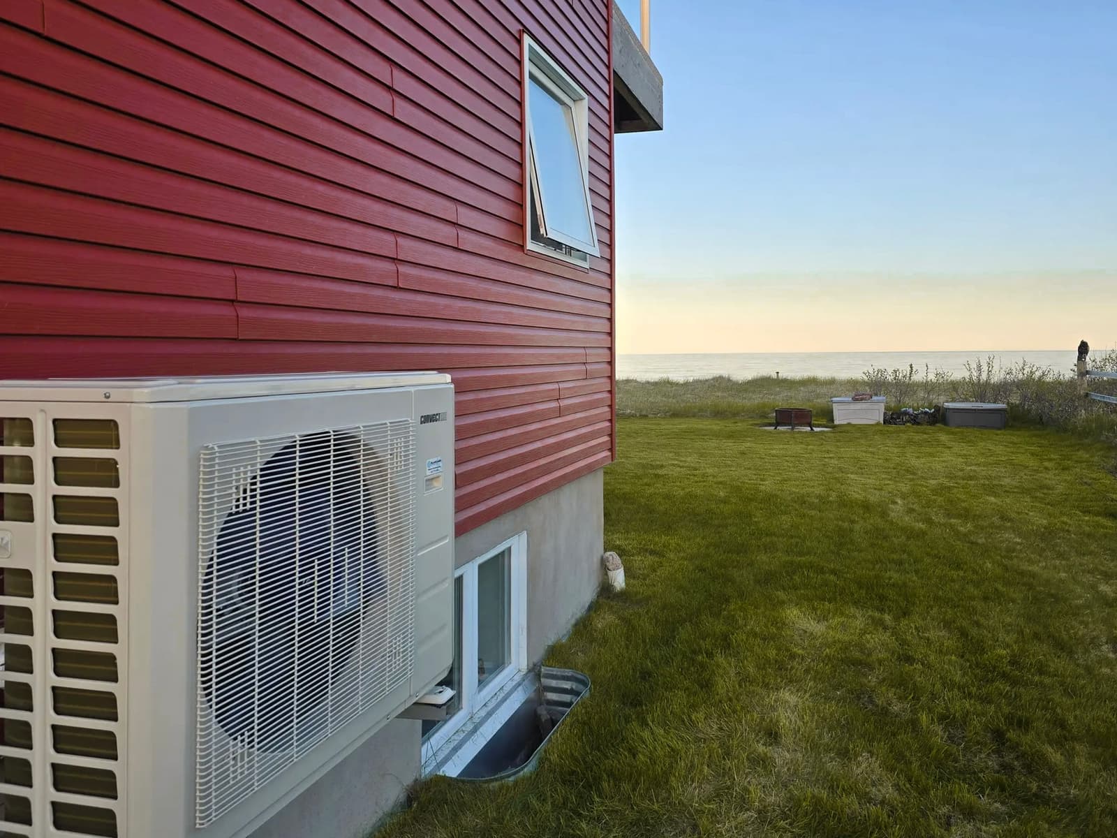 Samsung outdoor air conditioning unit with fan, facing a green garden and the sea