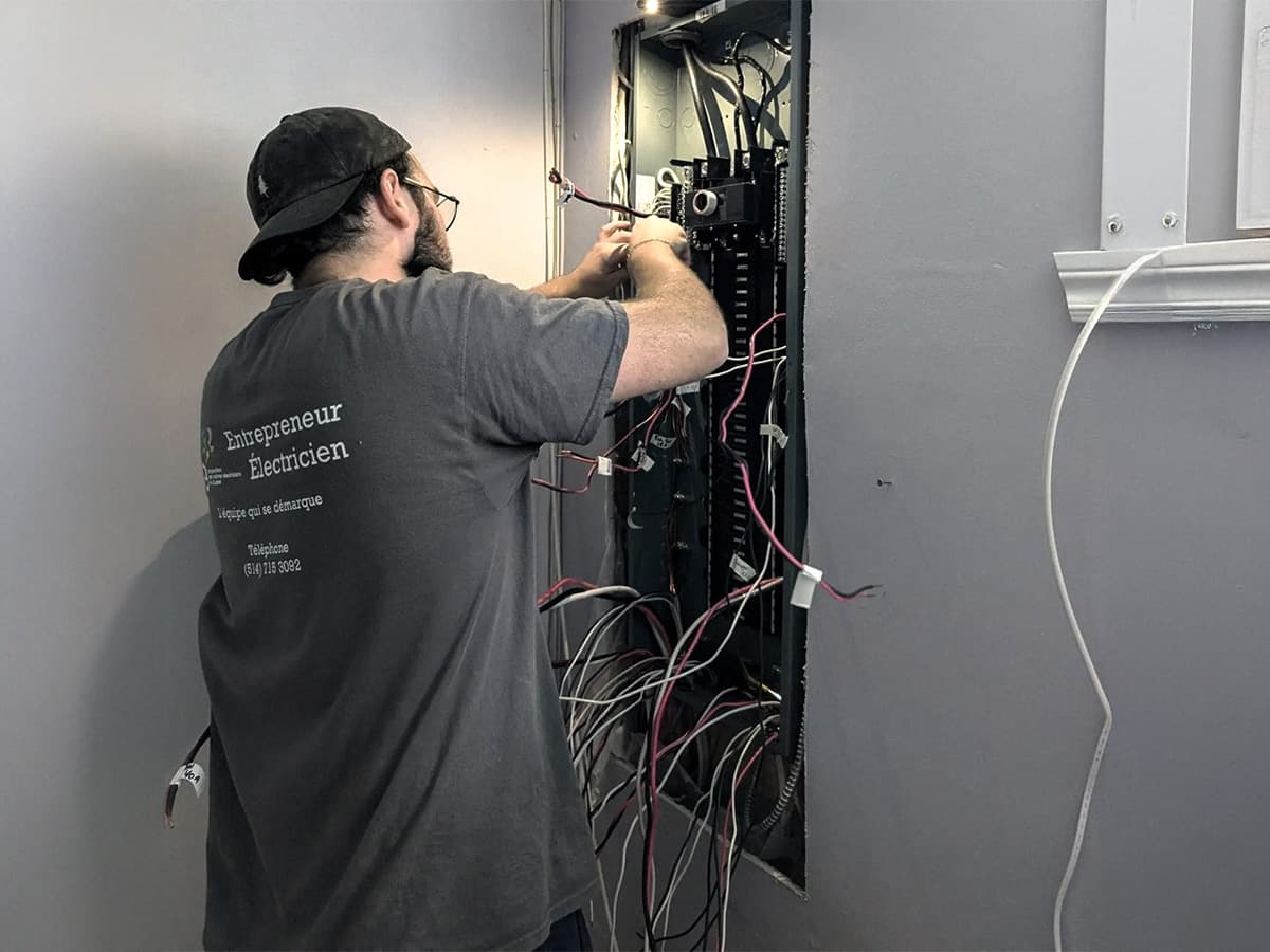 An electrician performing repairs on a residential electrical panel with exposed wiring.