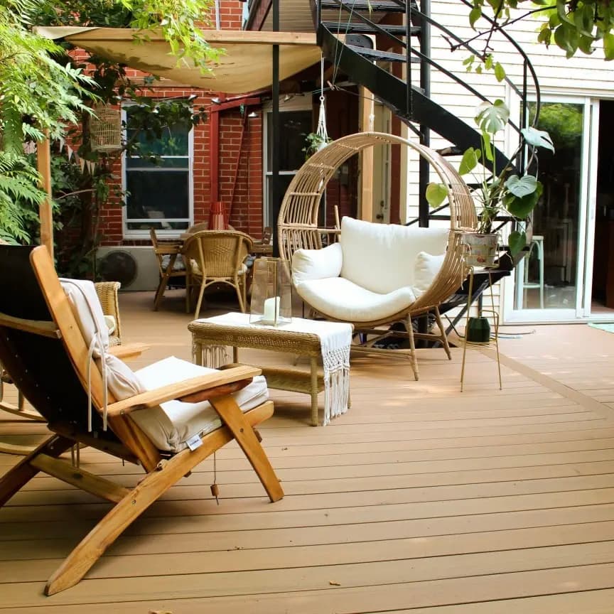 Wooden deck with rattan furniture, hanging chair, wooden armchair, and plant decorations, creating a warm and relaxing ambiance.
