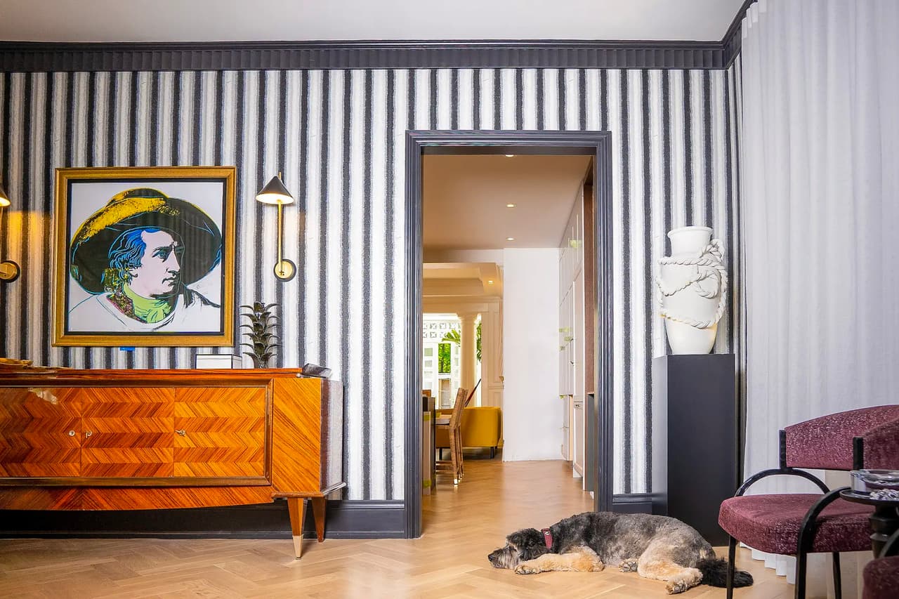 Sophisticated interior with striped wallpaper, designer wooden furniture, and herringbone parquet flooring.