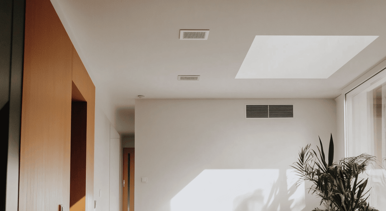 Bright contemporary living room with ceiling and wall vents for ducted heat pump system