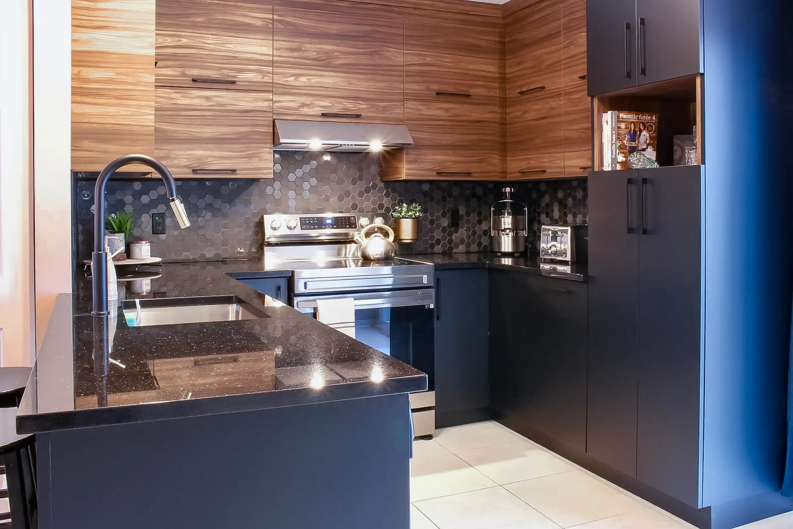 Modern kitchen with wood and black cabinets, hexagonal tile backsplash, and black quartz countertop.