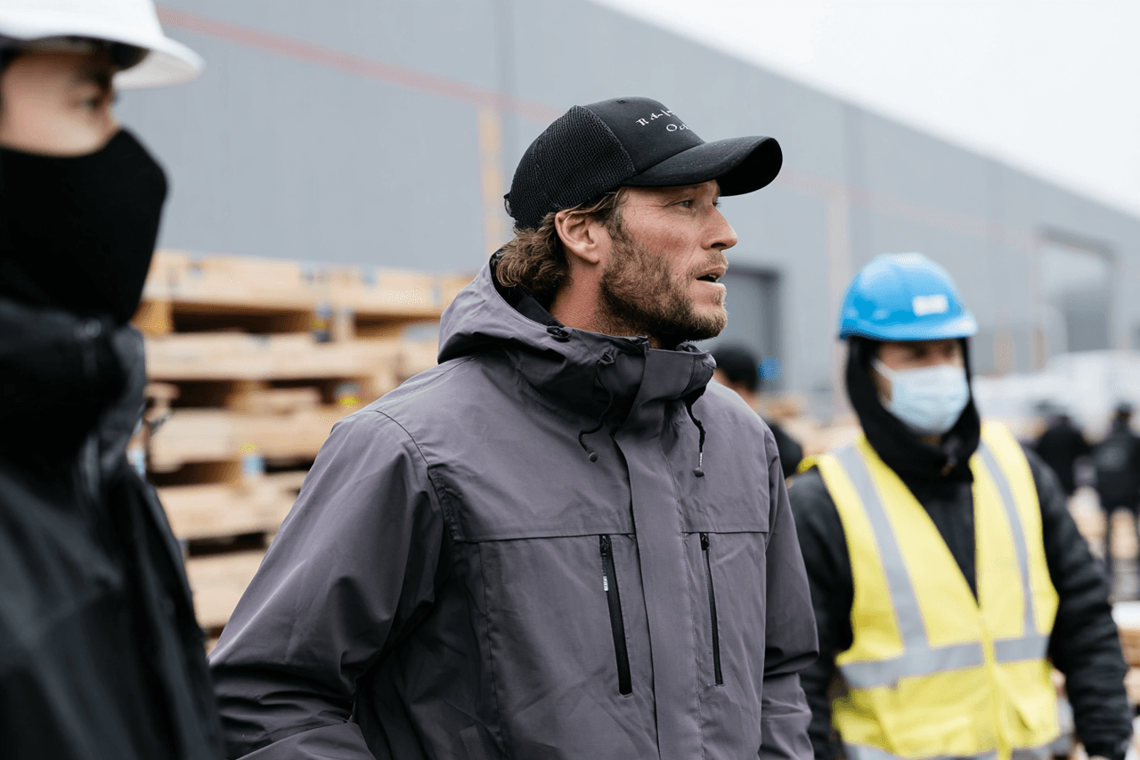 Construction workers wearing protective equipment on a job site, including helmets, reflective vests, and safety masks.