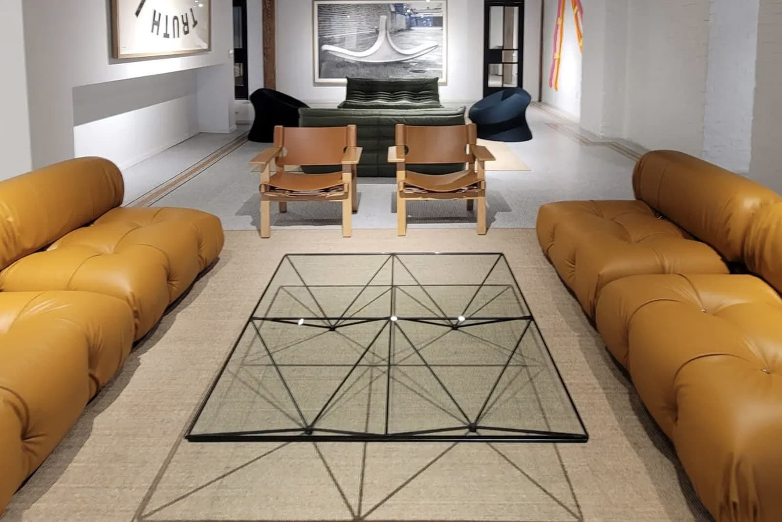 Industrial-style lounge with tufted leather sofas, geometric glass coffee table, wall art.
