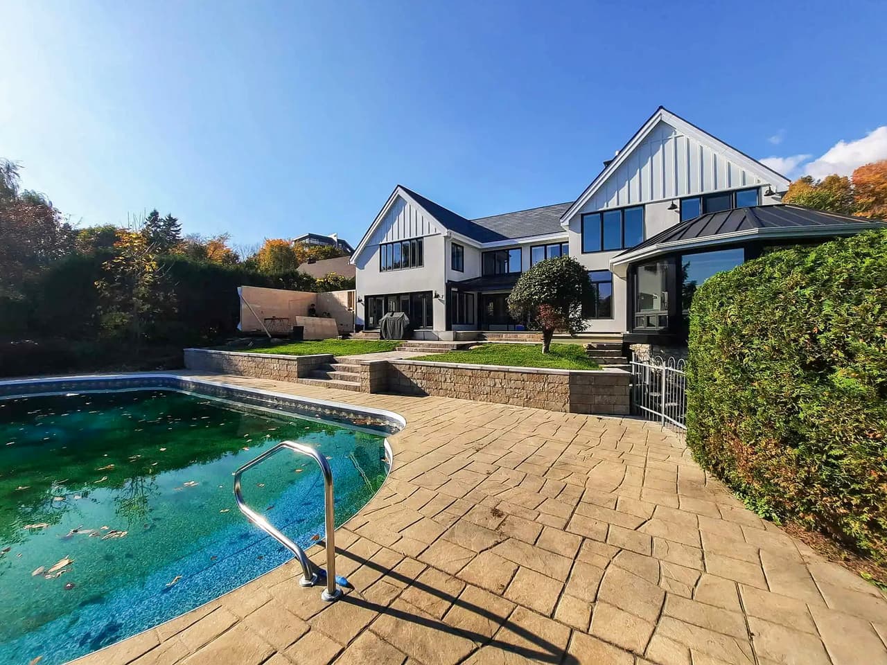Residential backyard with in-ground pool, stamped concrete patio and landscaping