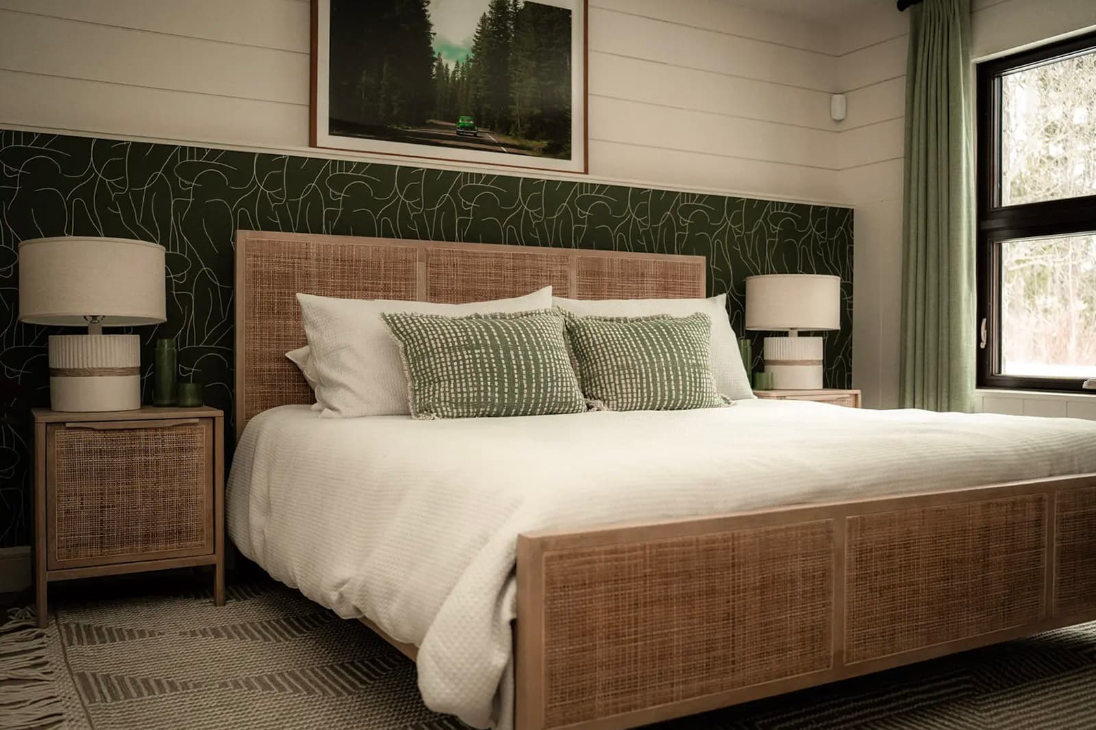 Cozy bedroom with a woven wood bed, green accent wall, and natural decor.