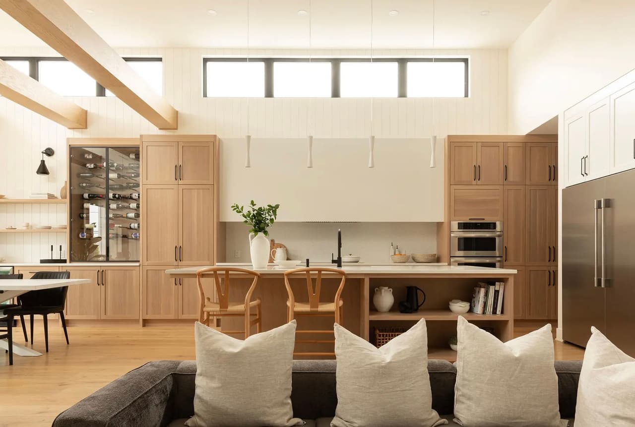 Modern light wood kitchen with central island, large wine cabinet, built-in appliances and minimalist design