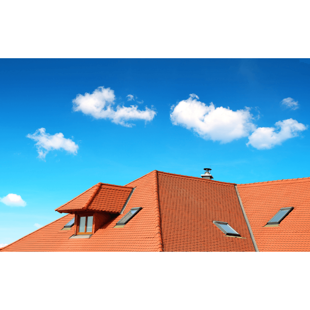 Terracotta tile roof with modern roof windows and a dormer under a blue sky with scattered clouds.