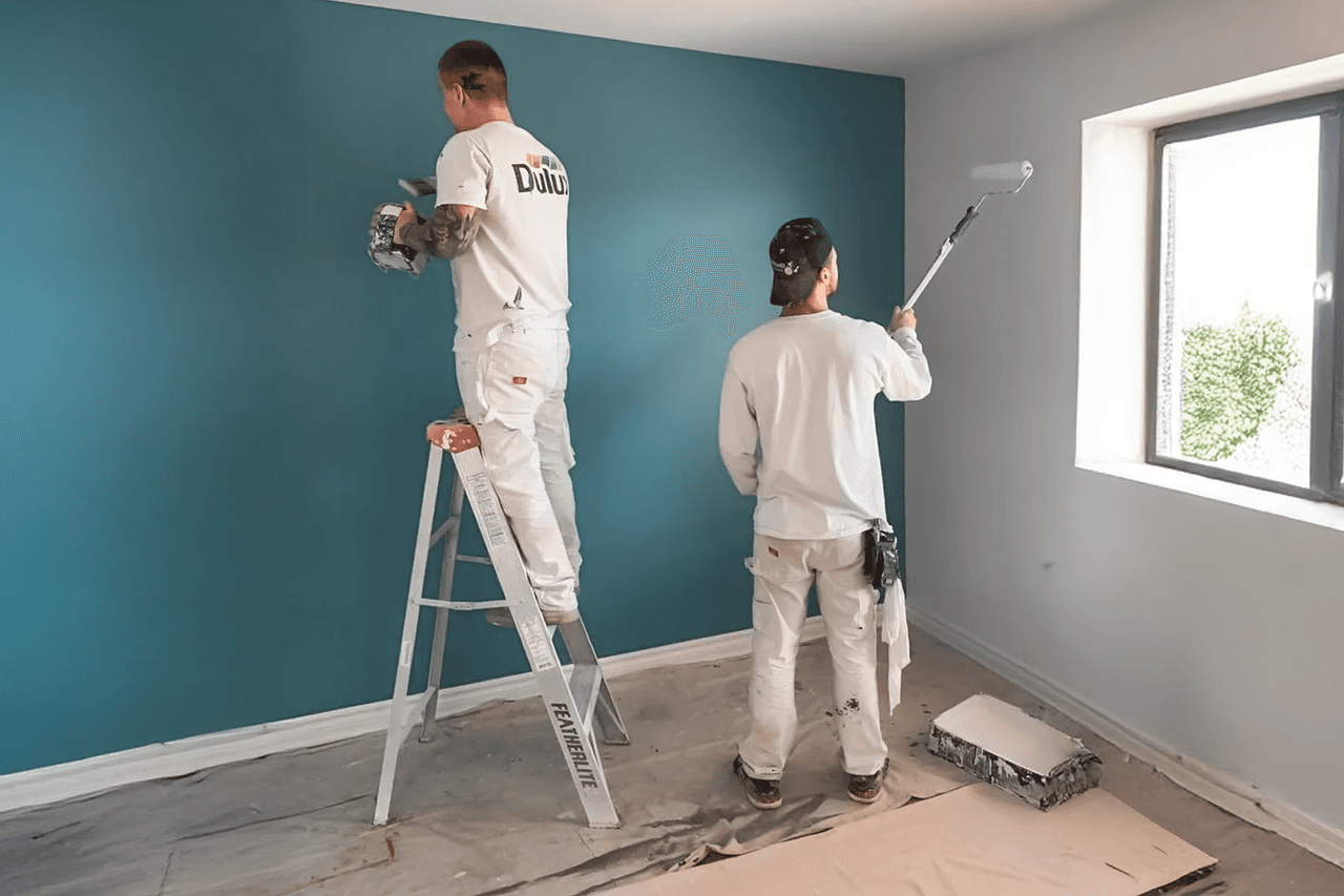 Interior painting work by professional painters applying blue paint on a wall for a modern renovation.
