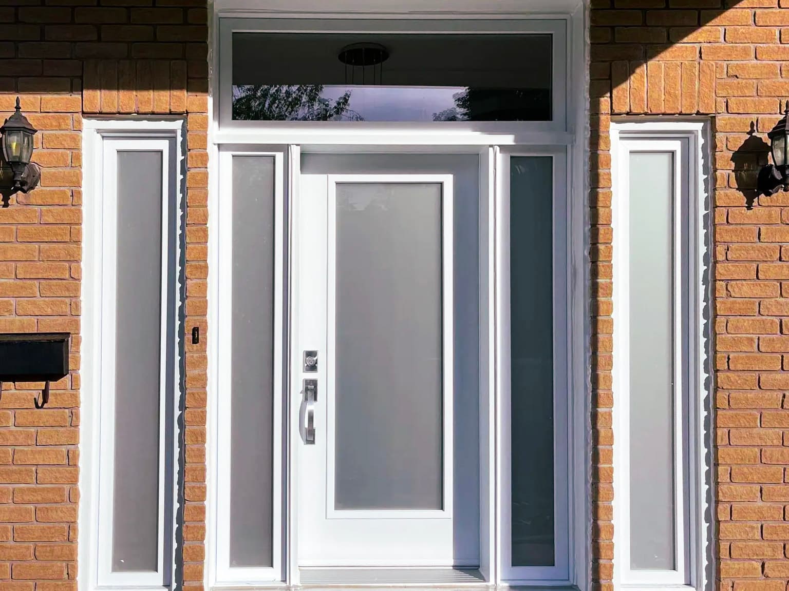 White front door with frosted glass and PVC frame in a brick house.