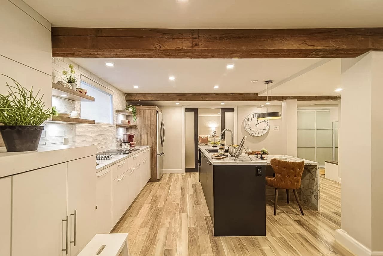 Modern kitchen with central island, wooden ceiling beams, white cabinets, recessed lighting, and wood-look flooring