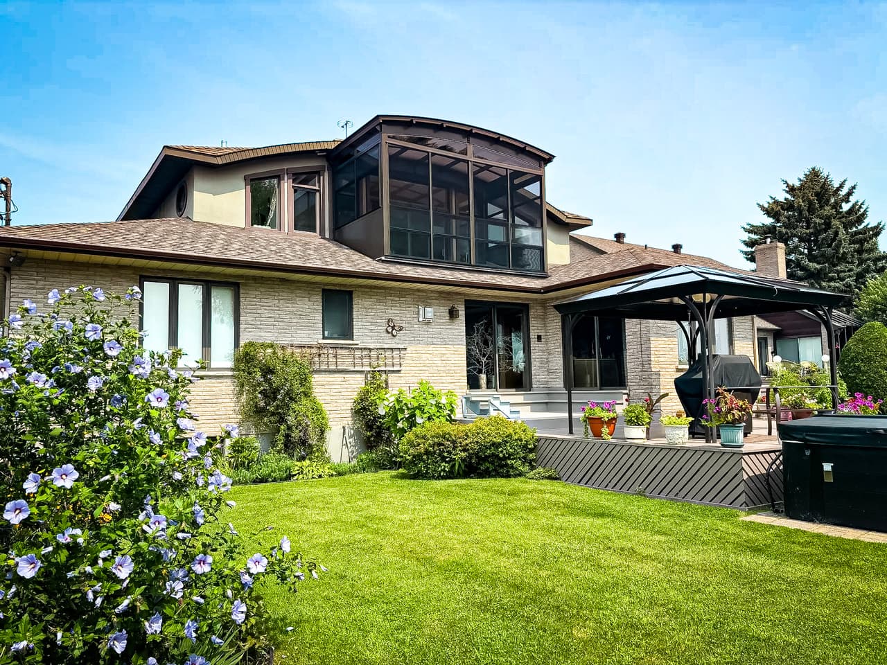 Family house with enclosed veranda, terrace, modern gazebo, and landscaped garden.