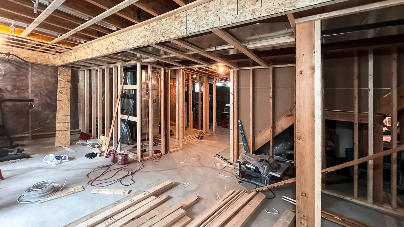 Basement under renovation with wooden framing, electrical wiring, and ongoing finishing work.