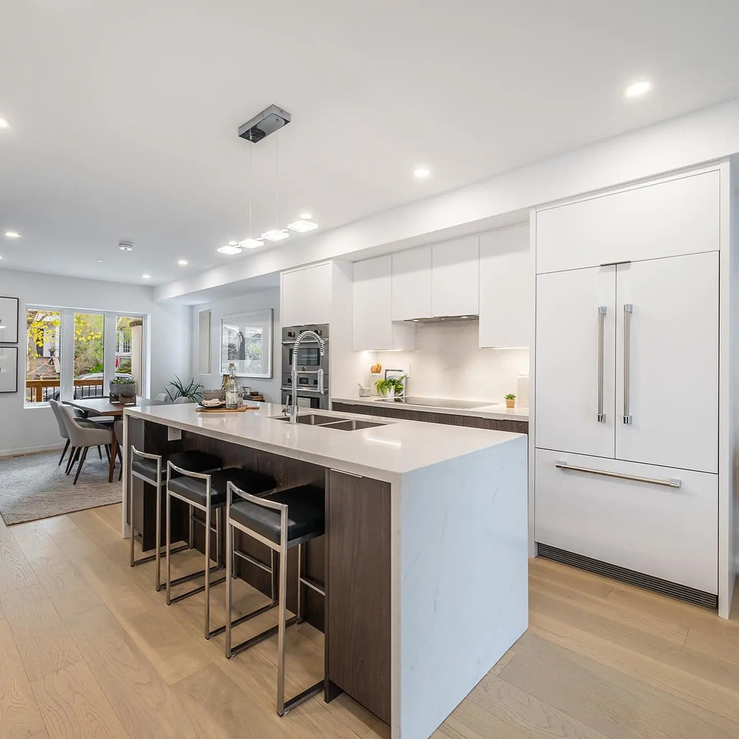A minimalist, elegant kitchen combining white, natural wood and quartz. The contrast between materials creates a warm, modern ambience.
