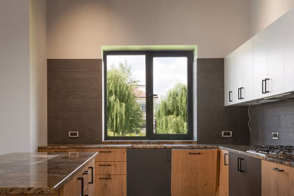 Modern kitchen with wooden cabinets, granite countertops, integrated appliances, and a large window providing a panoramic view.