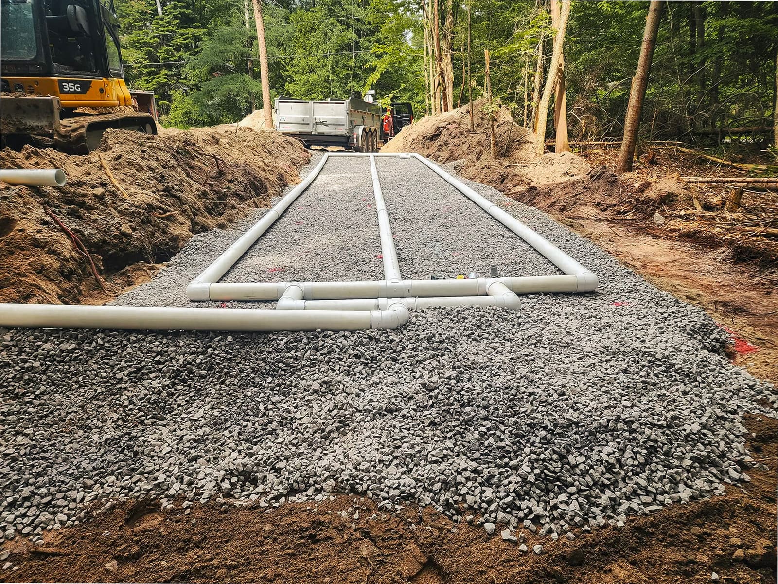 Septic system installation with PVC pipes and gravel for drainage.