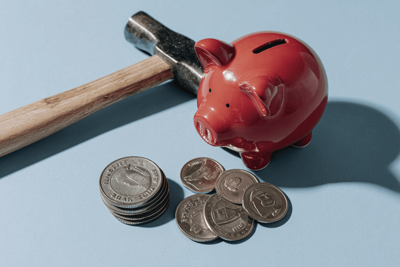 Red piggy bank with hammer and coins illustrating financial management and savings concept.