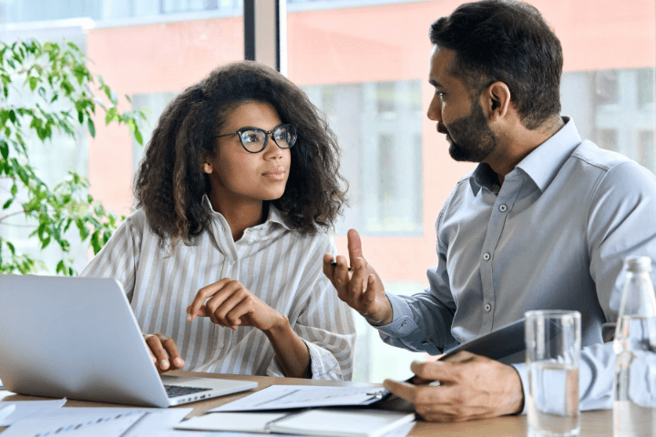 two person talking in front of a computer 
