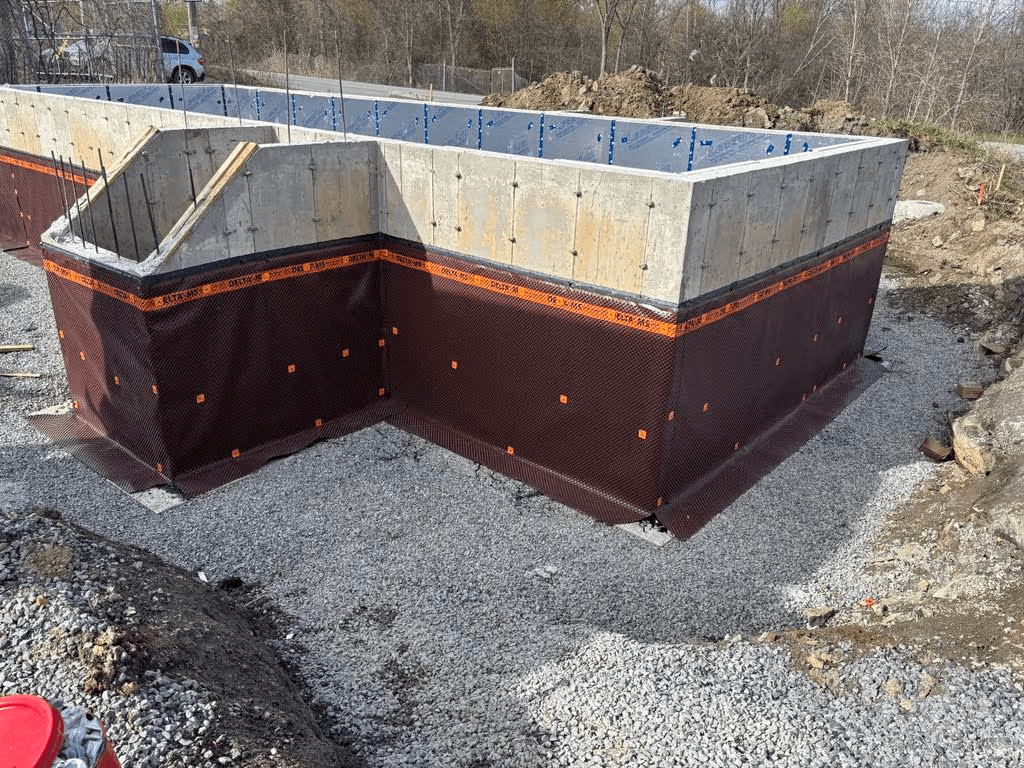 Concrete foundation with waterproofing membrane, gravel drainage and basement walls under construction