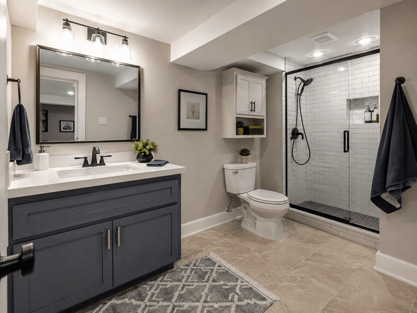 Renovated basement bathroom with a large glass shower, white tile, dark blue vanity, wall mirror, toilet, and modern lighting