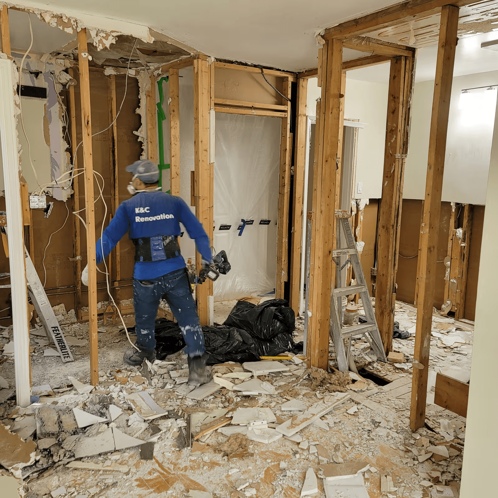  Interior demolition work with exposed wall framing and renovation contractor removing debris.