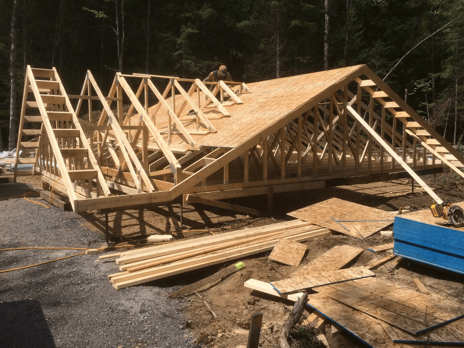 Wooden house frame construction with roof sheathing installation in a forested area
