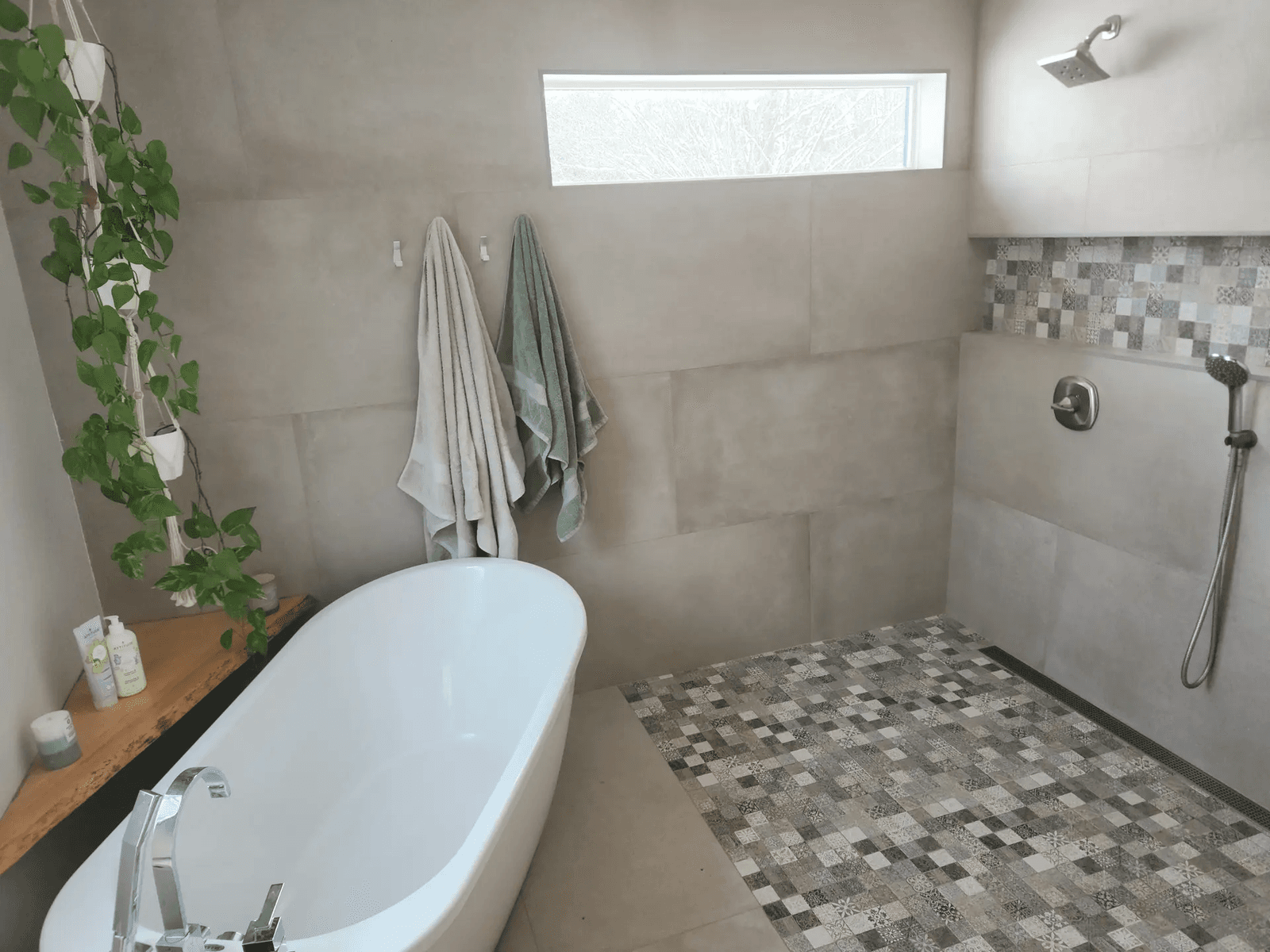 Modern bathroom with a freestanding tub, walk-in shower, mosaic tile and natural plant decor.