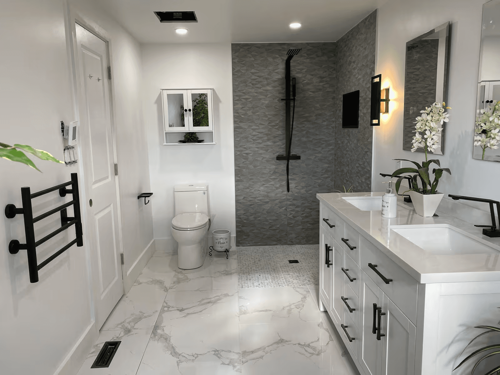 Renovated modern bathroom with a double vanity, tiled walk-in shower, black fixtures, toilet and marble-look flooring