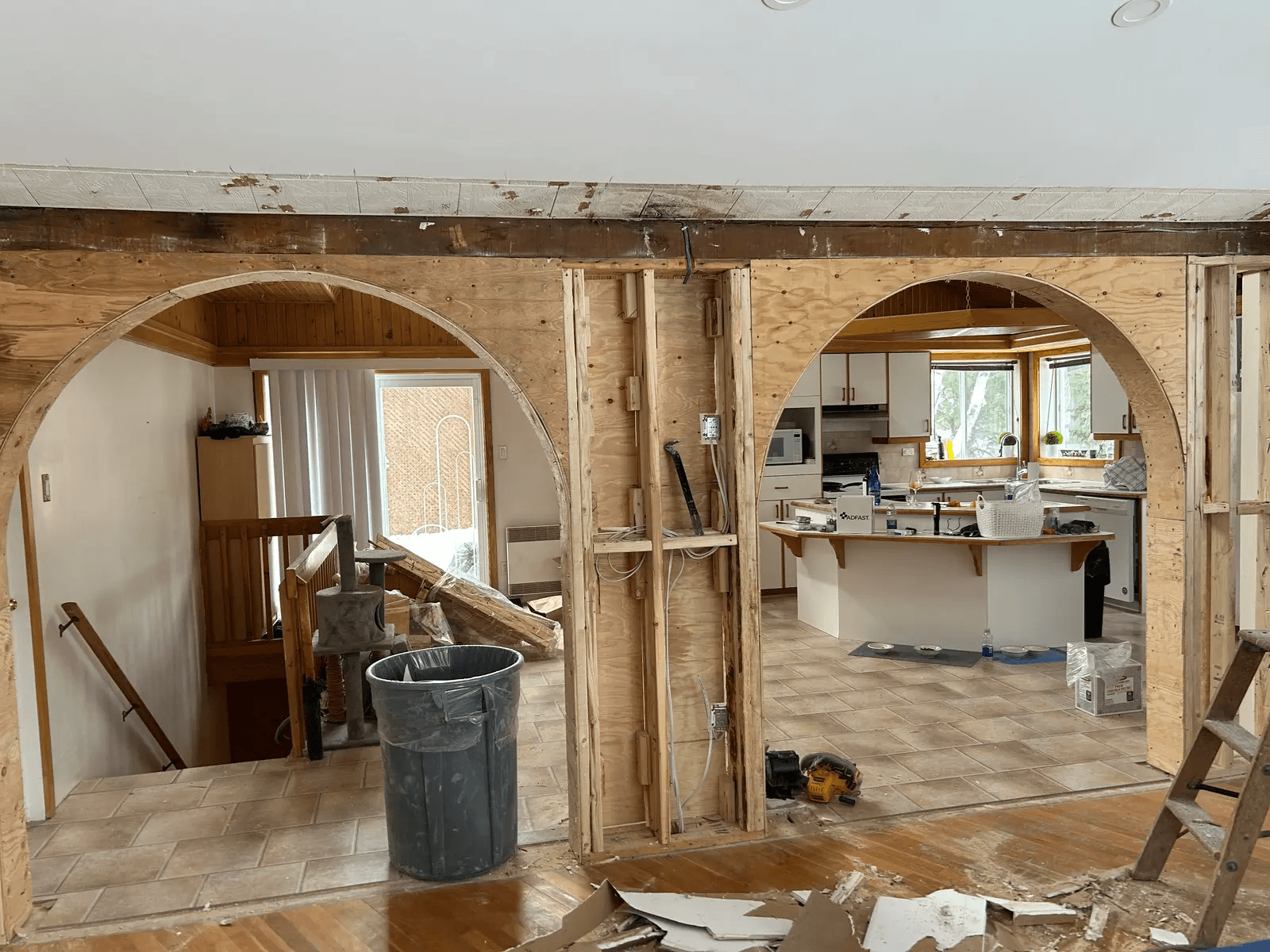 Interior home renovation with opened walls, large structural wood arches, exposed framing, visible wiring and a kitchen area under renovation