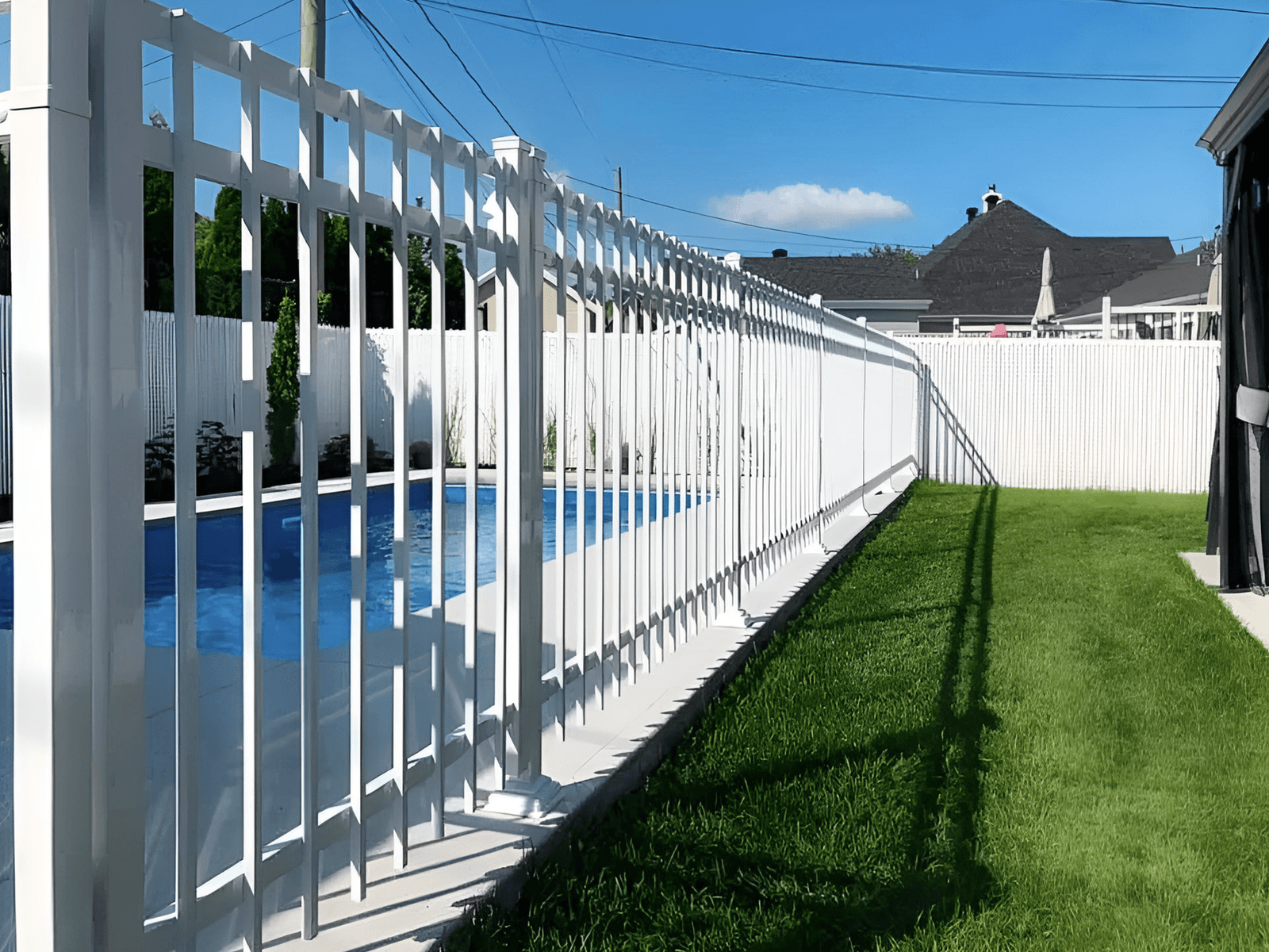 White safety fence surrounding a residential backyard swimming pool.
