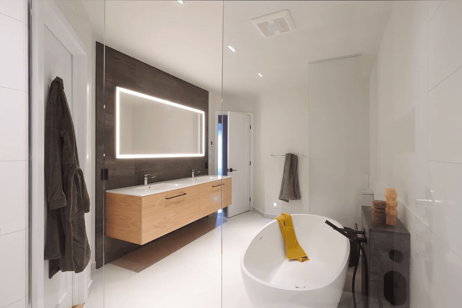 Contemporary bathroom with freestanding bathtub, floating double wood vanity, large illuminated mirror and glass shower