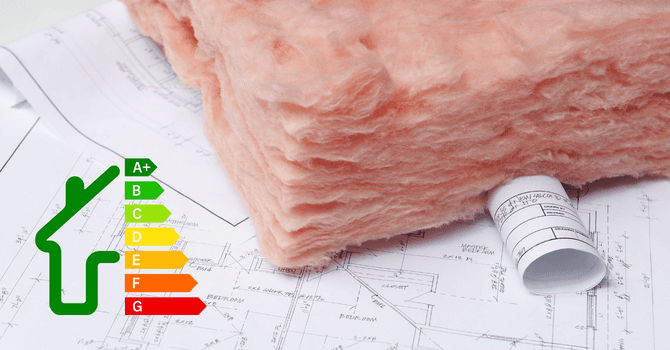 Pink fiberglass insulation batt placed on top of an architectural blueprint next to a green energy efficiency rating icon graded A+ to G