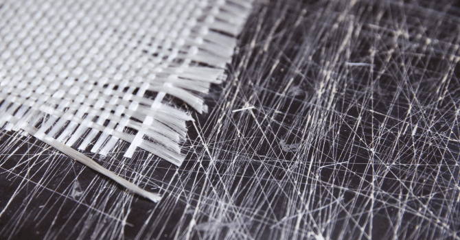 Close-up of white fibreglass fabric and glass filaments, illustrating the manufacturing of composite materials.